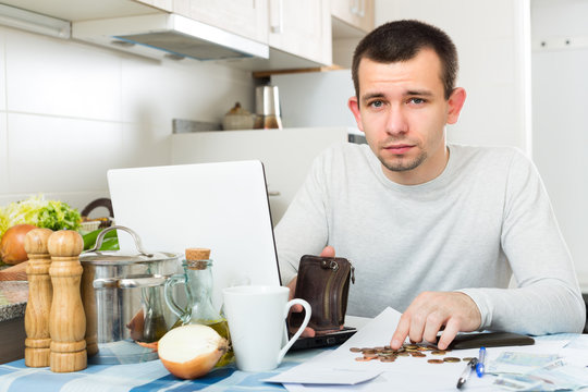 Unhappy guy with notebook at kitchen.