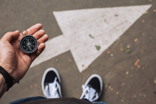 Traveler holding compass in the hand making choice in what direction to go