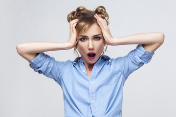 Blonde woman screaming with shock, holding hands on her head.