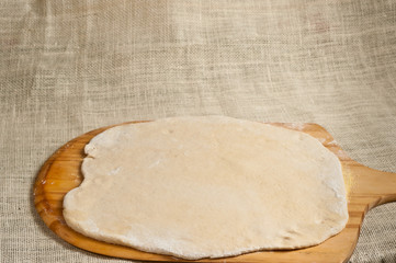 Baked homemade pizza dough / Baked homemade pizza dough rolled out onto a pizza peeling board