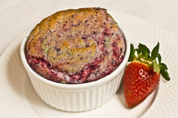 Mixed Berry soufflé, Paleo diet / Mixed Berry soufflé with a ripe, local strawberry in a white ramekin on a round, white plate, paleo diet
