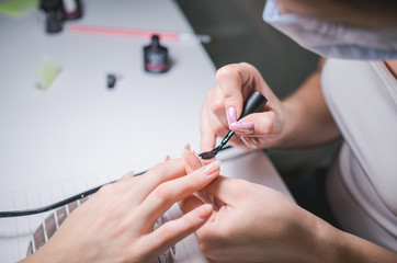 Manicurist hand painting client's nails