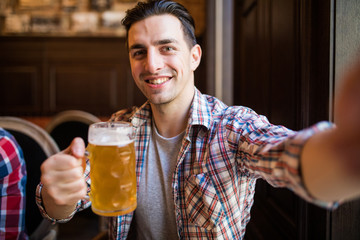 people and technology concept - man with smartphone drinking beer and taking selfie at bar or pub