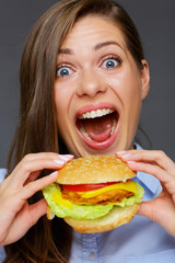 Happy woman with open mouth holding big burger with two hands.