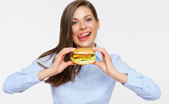 Smiling woman holding burger licking lips.