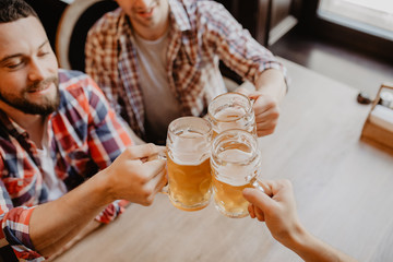 happy male friends drinking beer and clinking glasses at bar or pub