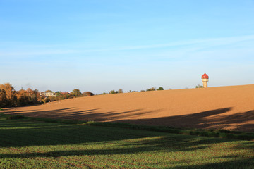Krajobraz wiejski jesienią, pola i miasteczko na horyzoncie.