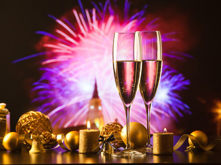 two champagne glasses against holiday lights and fireworks - new year celebration