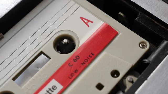 Audio tape player supply spindle slow-mo footage - Old music archives on cassette in casettophone close-up