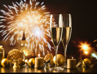 two champagne glasses against holiday lights and fireworks - new year celebration