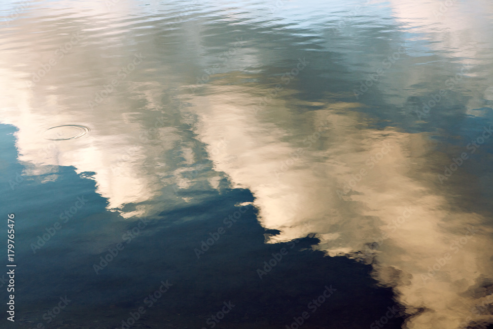 Wall mural reflection of blue sky with white clouds in water, abstract background.