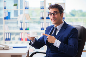 Fototapeta na wymiar Businessman drinking coffee in the office during break