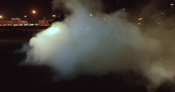 Slow motion, motorcycle peels out at night