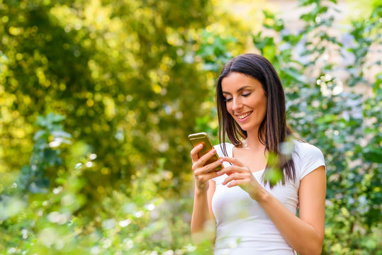 A cheerful woman in a Park using her Smartphone