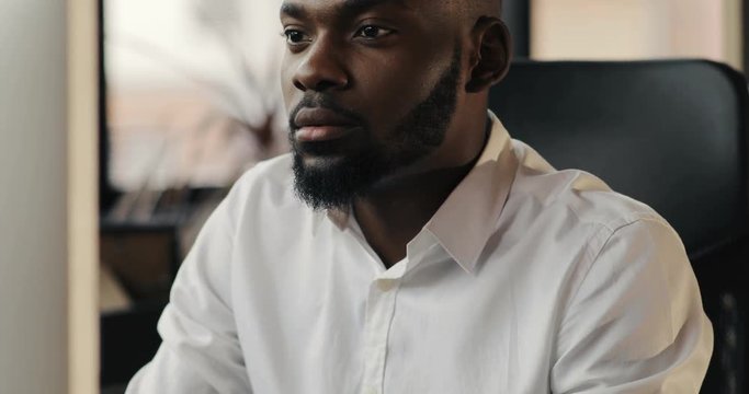 Portrait of face happy African American man with a beard working in an office focused on a job feel pleasure smile looking in monitor screen technology businessman successful business Slow Motion Shot