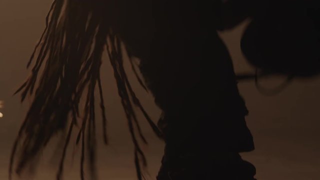 A guitar player with dreads rocks out and head-bangs in front of raining sparks