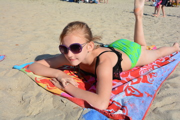 Mädchen liegt auf dem Bauch am Sandstrand