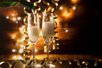 two champagne glasses with ribbons against holiday lights and fireworks - New Year celebrations