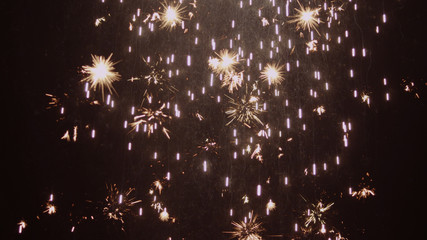 Sparks and fireworks rain down over dark background 4