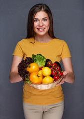 woman holding basket with summer vegetables.