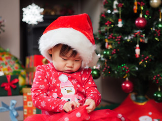 Obraz na płótnie Canvas Santa baby girl opening her Christmas gift