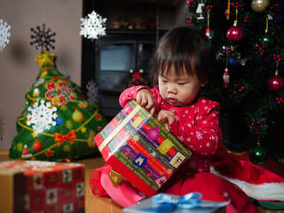 Fototapeta na wymiar Santa baby girl opening her Christmas gift