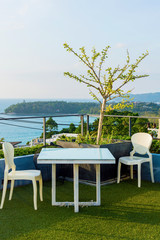 Fototapeta na wymiar White table and chair on terrace with view of the and sea