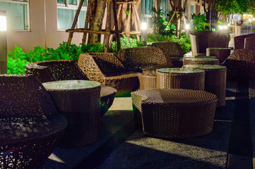 Rattan table and chaise longues near modern swimming pool, closeup