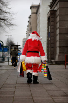 Santa is tired of shopping, walking home with his bags in the big City, Berlin