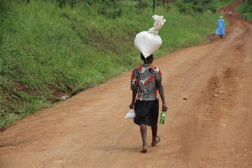Donna ugandese che trasporta un sacco sulla testa