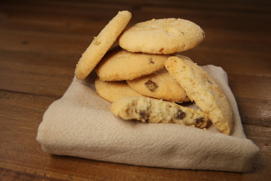 Selection of choc chip and fruit cookies, on a serviette on a wooden table