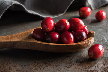Whole ripe cranberries on wood spoon
