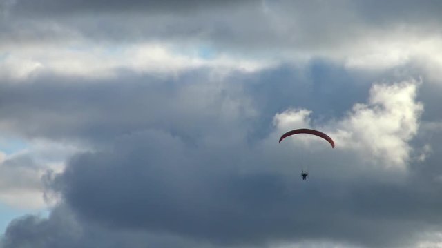 Paraglider flying high in the storm clouds. Air sport and recreation. A powered paraglider - a glider with a dorsal power plant, providing the rise and moving in the air.