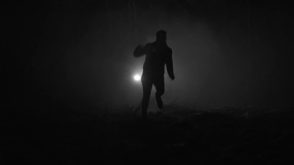 Silhouette of a man running through the forest at winter night