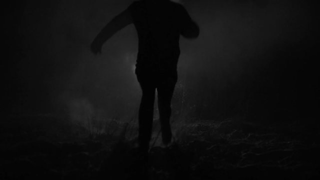 Silhouette of a man running through the forest at winter night