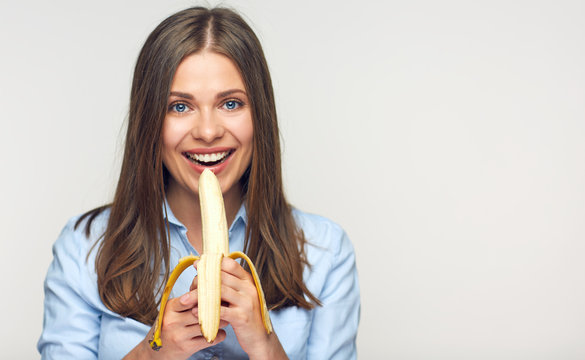 Smiling woman eating peeled banana.