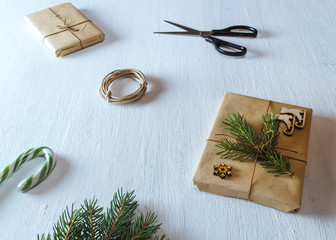 Christmas gifts, fir branches, scissors, ribbon, candy on blue desk. Flat lay, top view