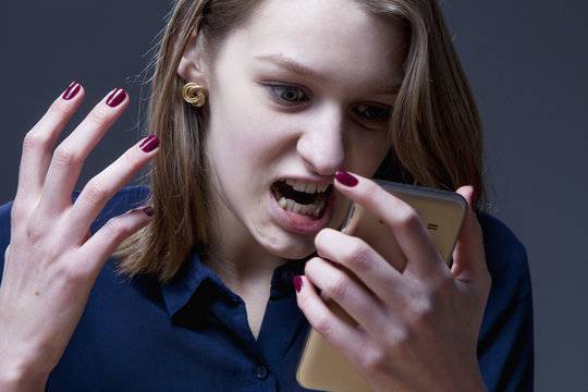 Close up of young desperate and angry woman screaming and talking on telephone