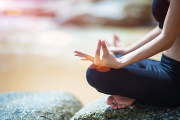 woman in yaga practice at the sea beach, gesturing finger in stable meditation to balance life living