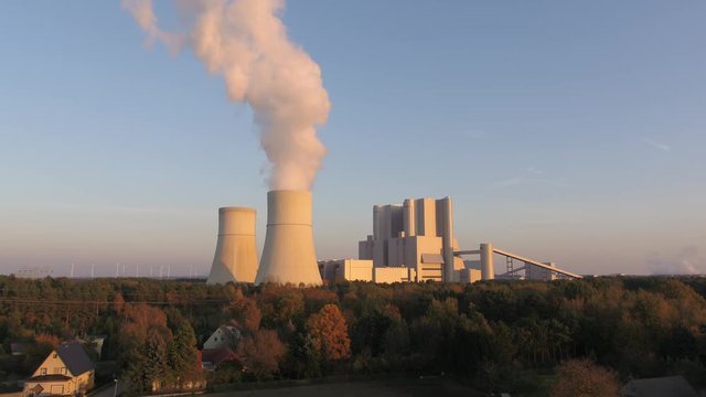 Aerial coal power plant drone moving slowly towards it sunset 