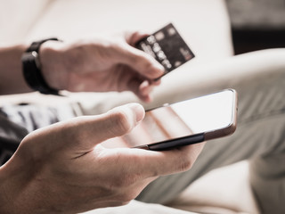 Close up of male hands using smartphone and holding credit card. Online shopping concept