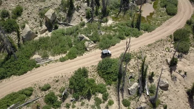 Aerial follow track 4x4 offroad recreation mountain road. Skyline Drive off road trail and road central Utah. Alpine peaks, meadows and valley forest. Travel and exploring wilderness outback country.