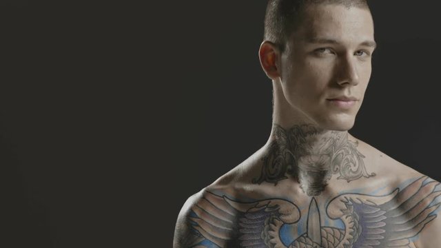 Handsome sexy young man stylish with tattoo on his neck, torso and hand - middle shot portrait studio - Prores - cinematic fashion lighting