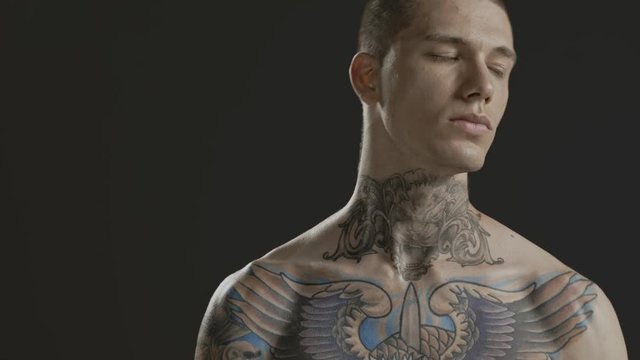 Handsome sexy young man stylish with tattoo on his neck, torso and hand - middle shot portrait studio - Prores - cinematic fashion lighting