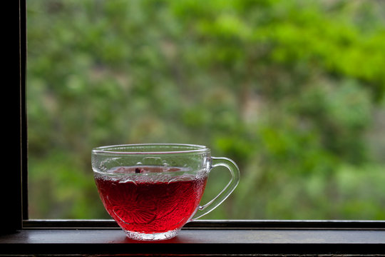 Hibiscus tea on wooden windowsill against green background