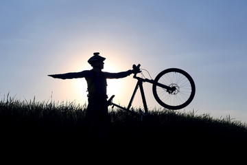 silhouette of a cyclist with a bike in the sun