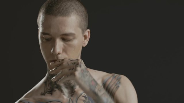Handsome sexy young man stylish with tattoo on his neck, torso and hand - middle shot portrait studio - Prores - cinematic fashion lighting