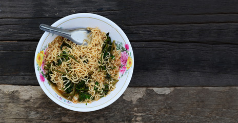 noodle and stainless steel spoon with vegetable in white bowl on old wood table