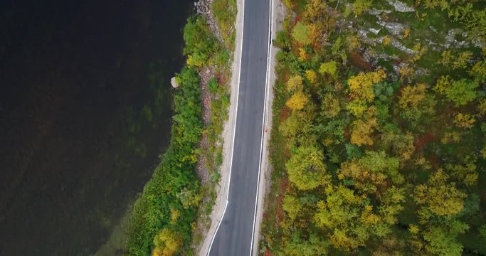 Autumn color road, Cinema 4k aerial tilt view of a car and a trailer, on 970 the tenontie road full of different fall colors, near tenojoki river, on a sunny evening dawn, in Lapland, Finland