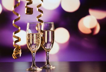 two champagne glasses with ribbons against holiday lights and fireworks - New Year celebrations